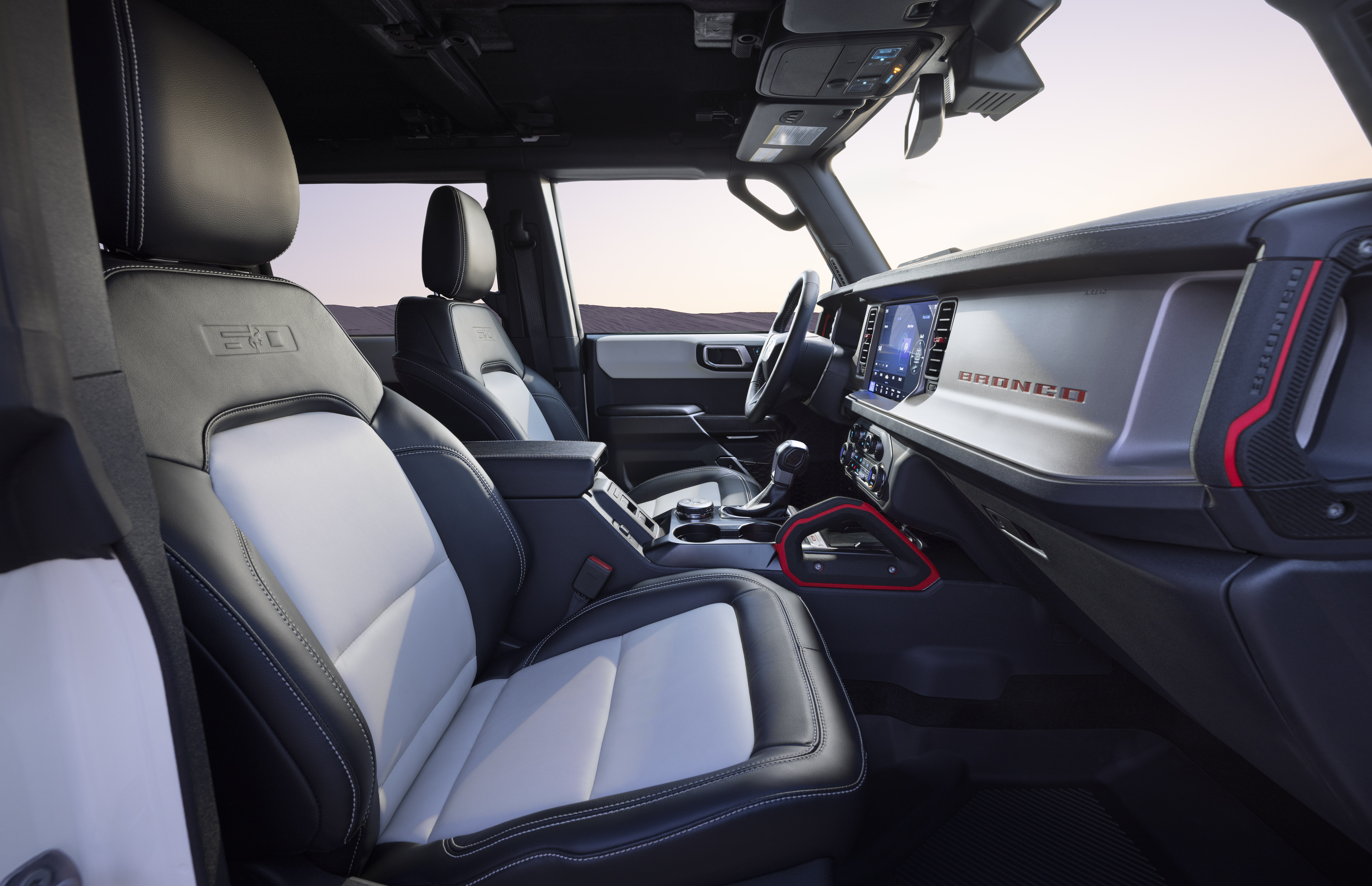 2026 Ford Bronco 60th Anniversary Package interior shown. Red accents on the dashboard complement gray and white seats.